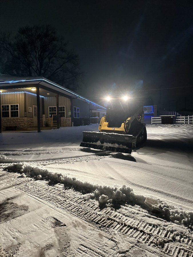 bobcat machine clearing a parking lot at night